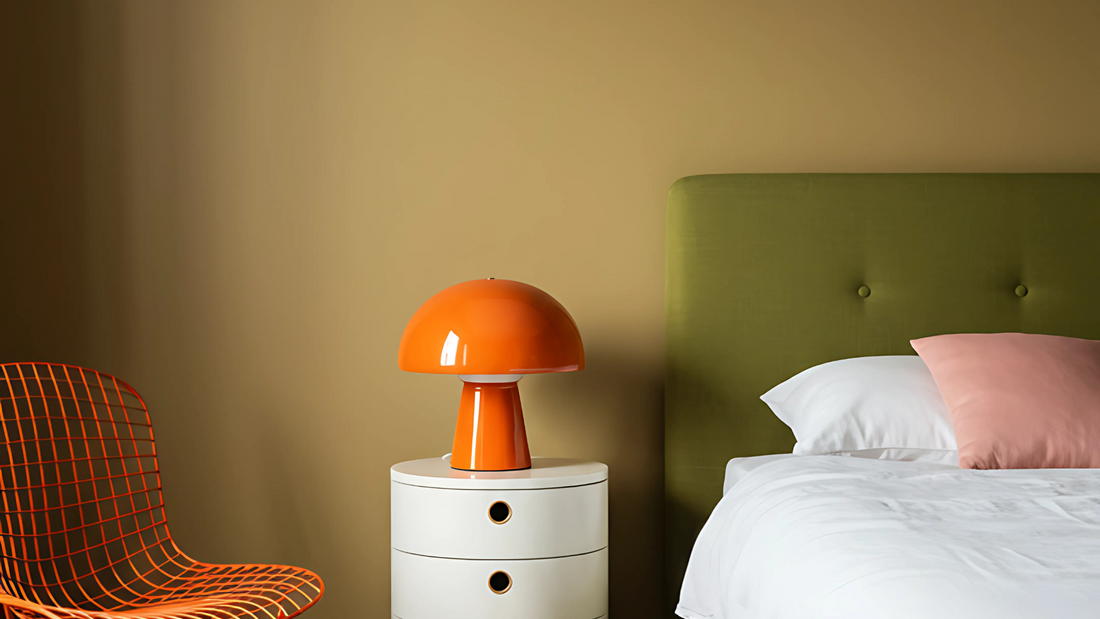 bedroom interior image with a muted yellow wall and photographed olive green bed, bright orange chair, white round bedside table and a bright orange night lamp
