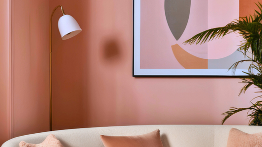 photo of a living room with a rounded warm neutral sofa, peach coloured cushions, peach walls and an abstract artwork in peach and pink