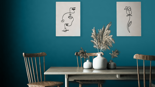 spacious dining room with dark teal walls, abstract fine line drawing artworks, wooden dining table and chairs and pampas grass decorations