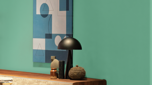 dark hallway corner with a wall painted in a teal green colour, wooden mid-century built in sideboard, vintage accessories placed on top of it and a geometric artwork in white and blue on the wall
