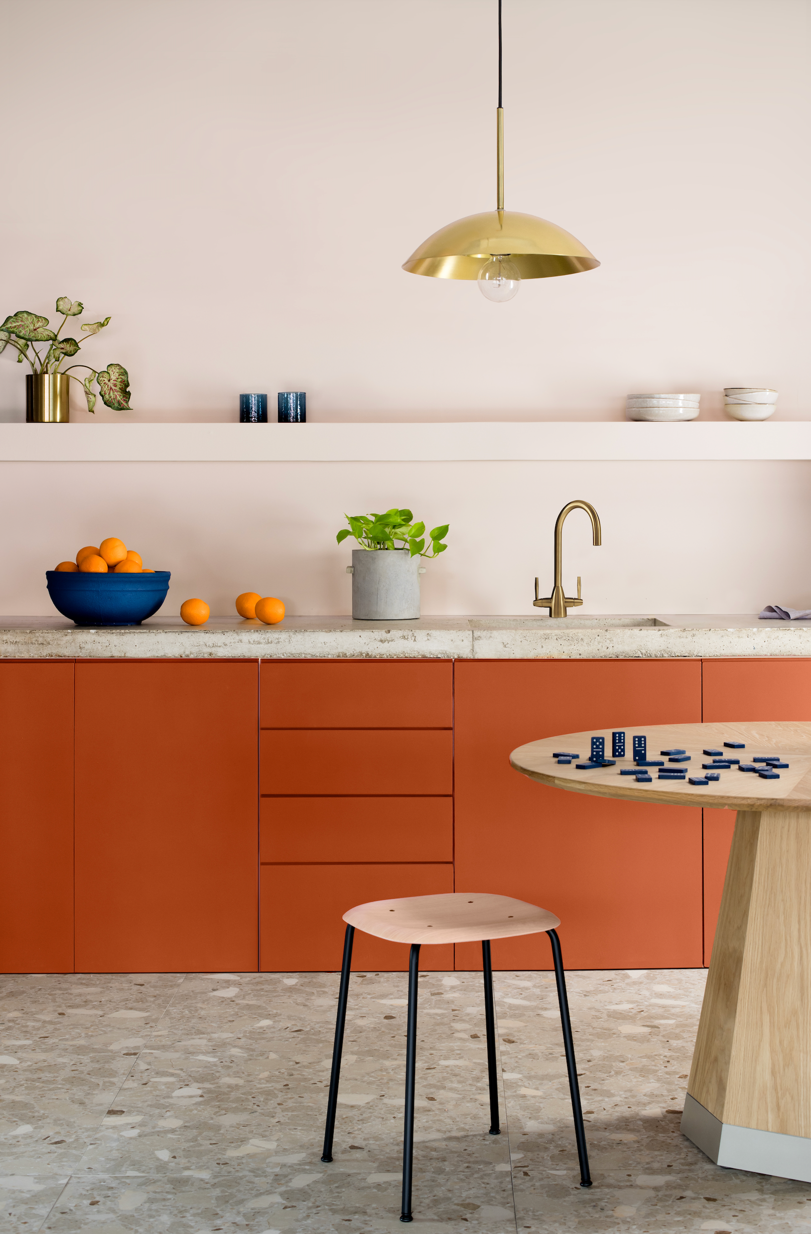 Modern kitchen with orange cabinets, a wooden stool, and a round table.
