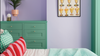 A bedroom scene with a bed in the foreground, a mint green dresser against a lavender wall, and a framed print of iced-out dessert glasses hanging on the wall.