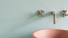Bathroom setting with a green and pink sink stopper on a light blue wall.